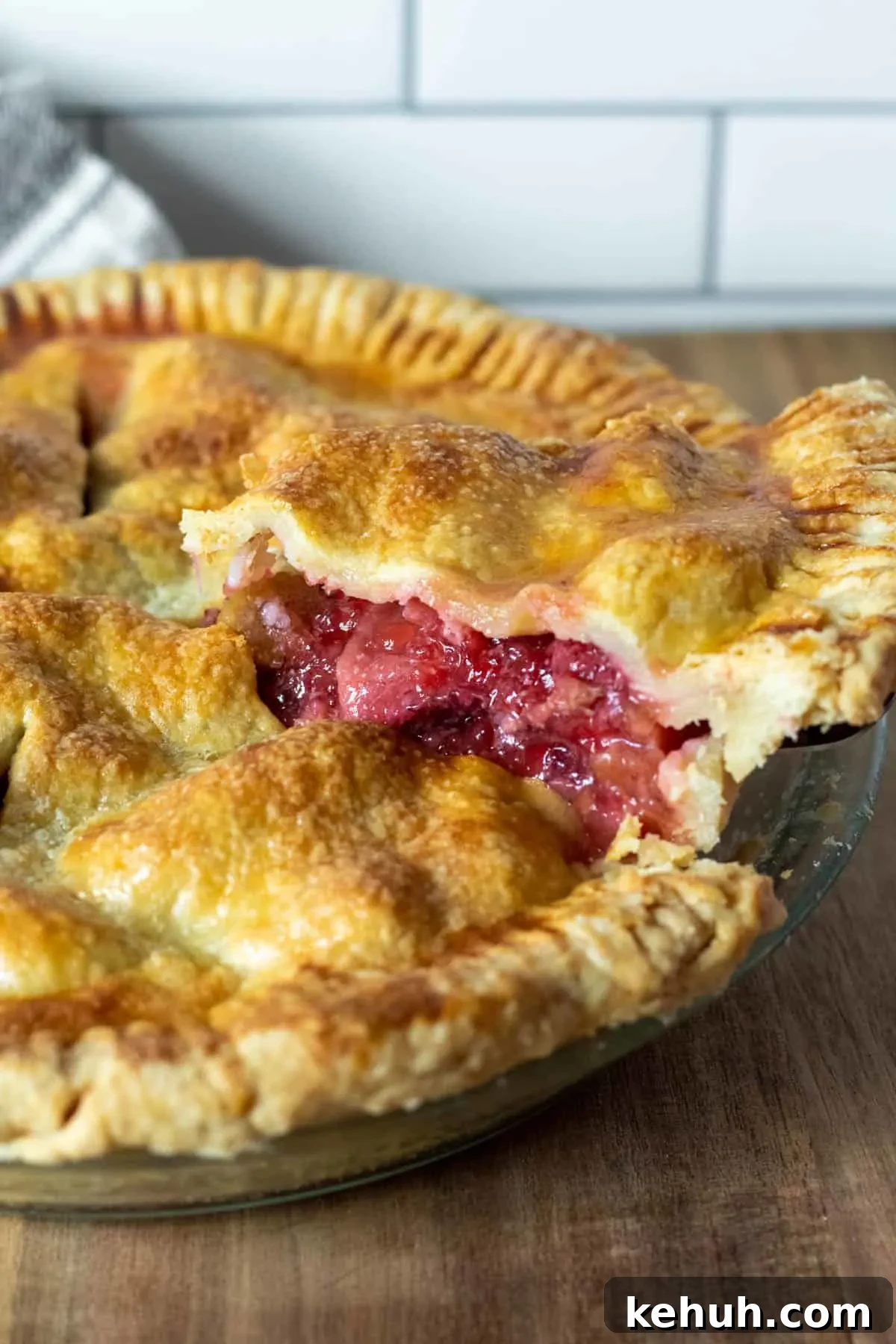 Close up of piece of strawberry rhubarb pie coming out of pie on pie server.