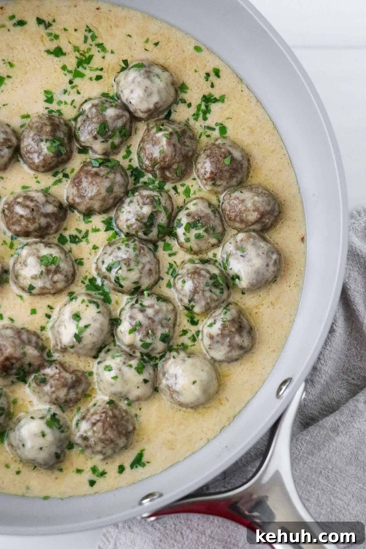 Classic Swedish Meatballs with Creamy Gravy (Köttbullar) 2 Swedish Meatballs with Gravy in a skillet sprinkled with parsley.
