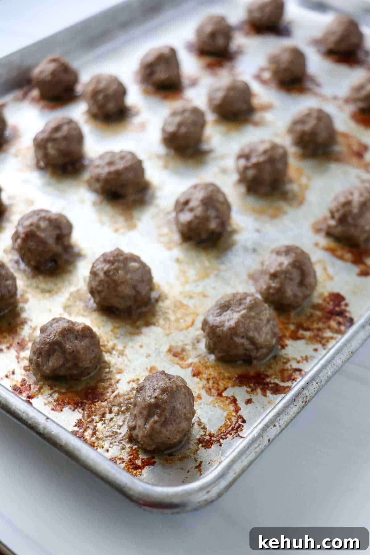 Classic Swedish Meatballs with Creamy Gravy (Köttbullar) 11 Cooked Swedish Meatballs on a baking sheet.