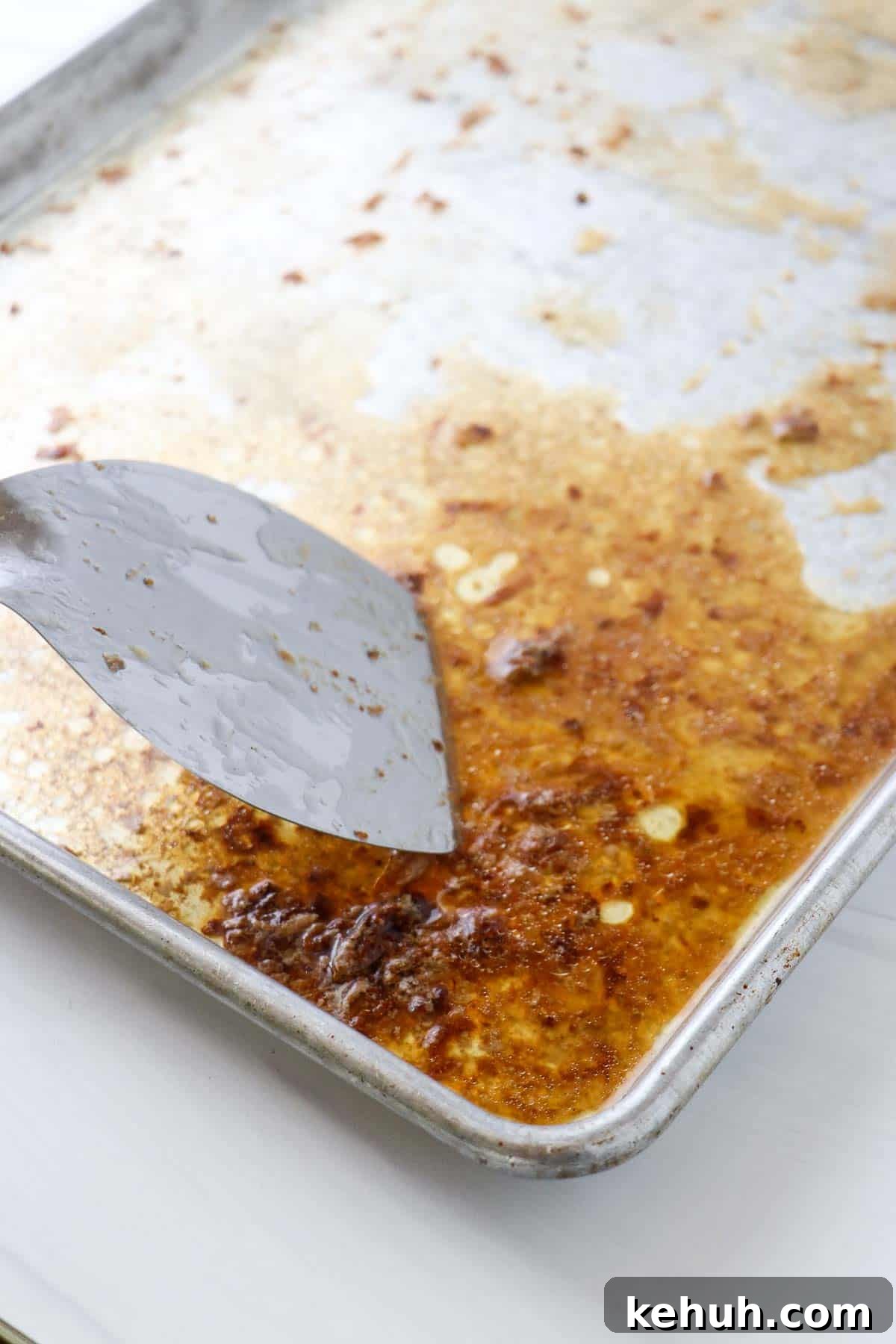 Classic Swedish Meatballs with Creamy Gravy (Köttbullar) 12 Baking sheet with brown bits and a metal spatula.