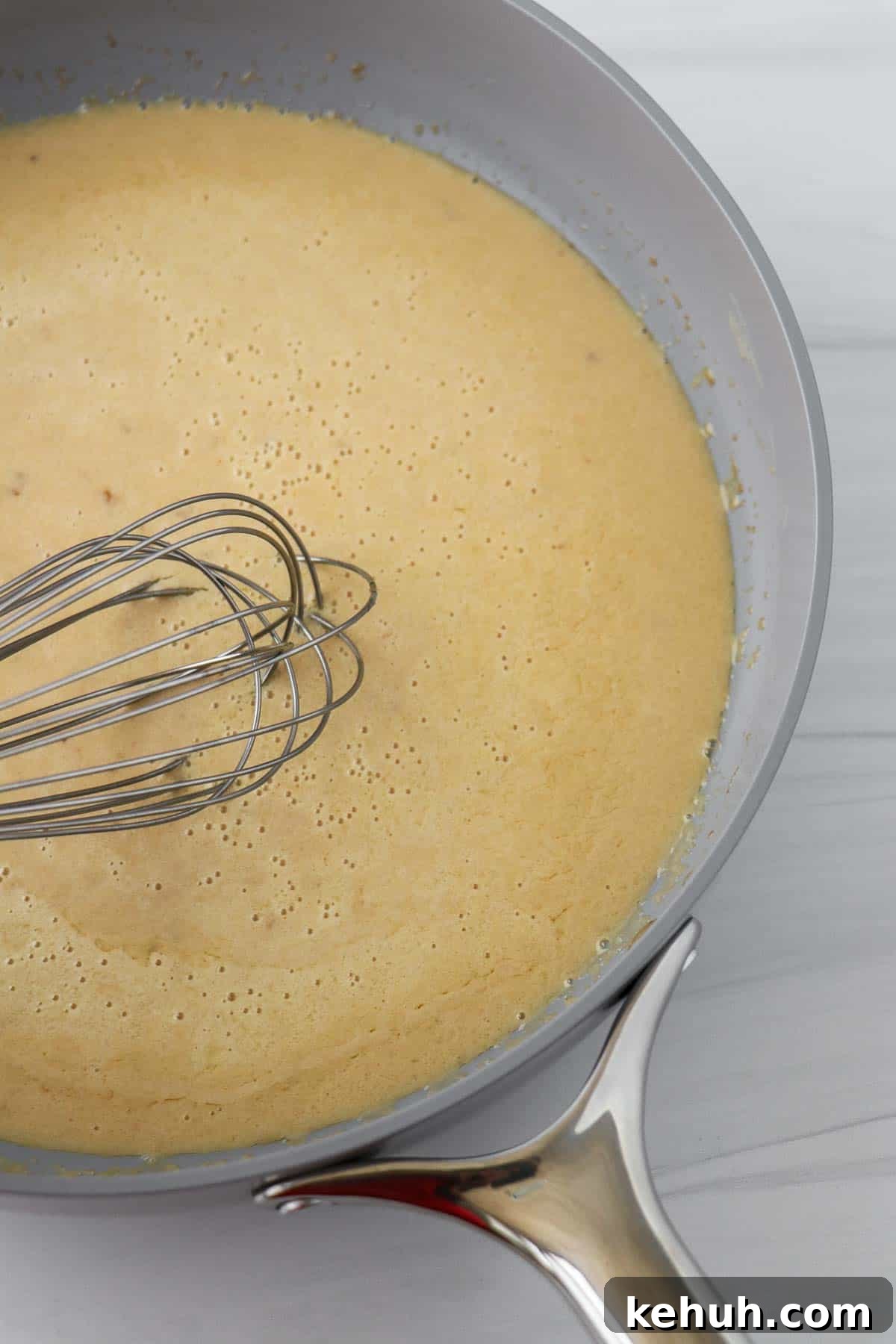 Classic Swedish Meatballs with Creamy Gravy (Köttbullar) 14 Gravy in a gray pan with a whisk.