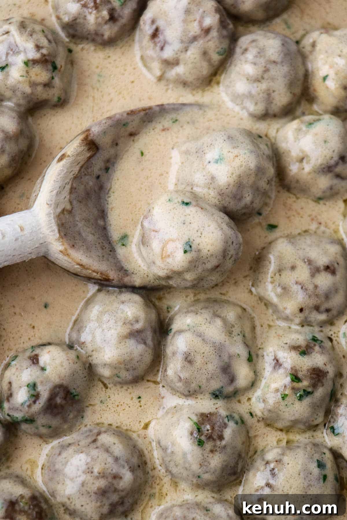 Classic Swedish Meatballs with Creamy Gravy (Köttbullar) 15 Close up of Swedish Meatballs with Gravy and a wooden spoon.