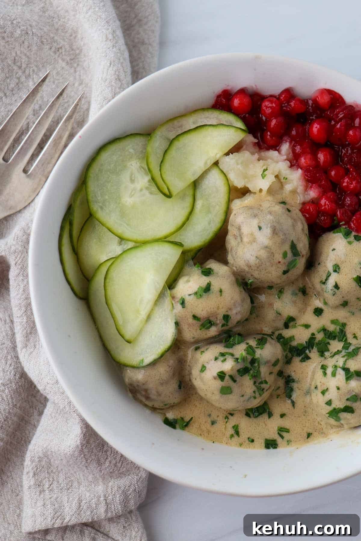 Classic Swedish Meatballs with Creamy Gravy (Köttbullar) 16 Overhead shot of Swedish Meatballs with Gravy and pickles and lingonberries.