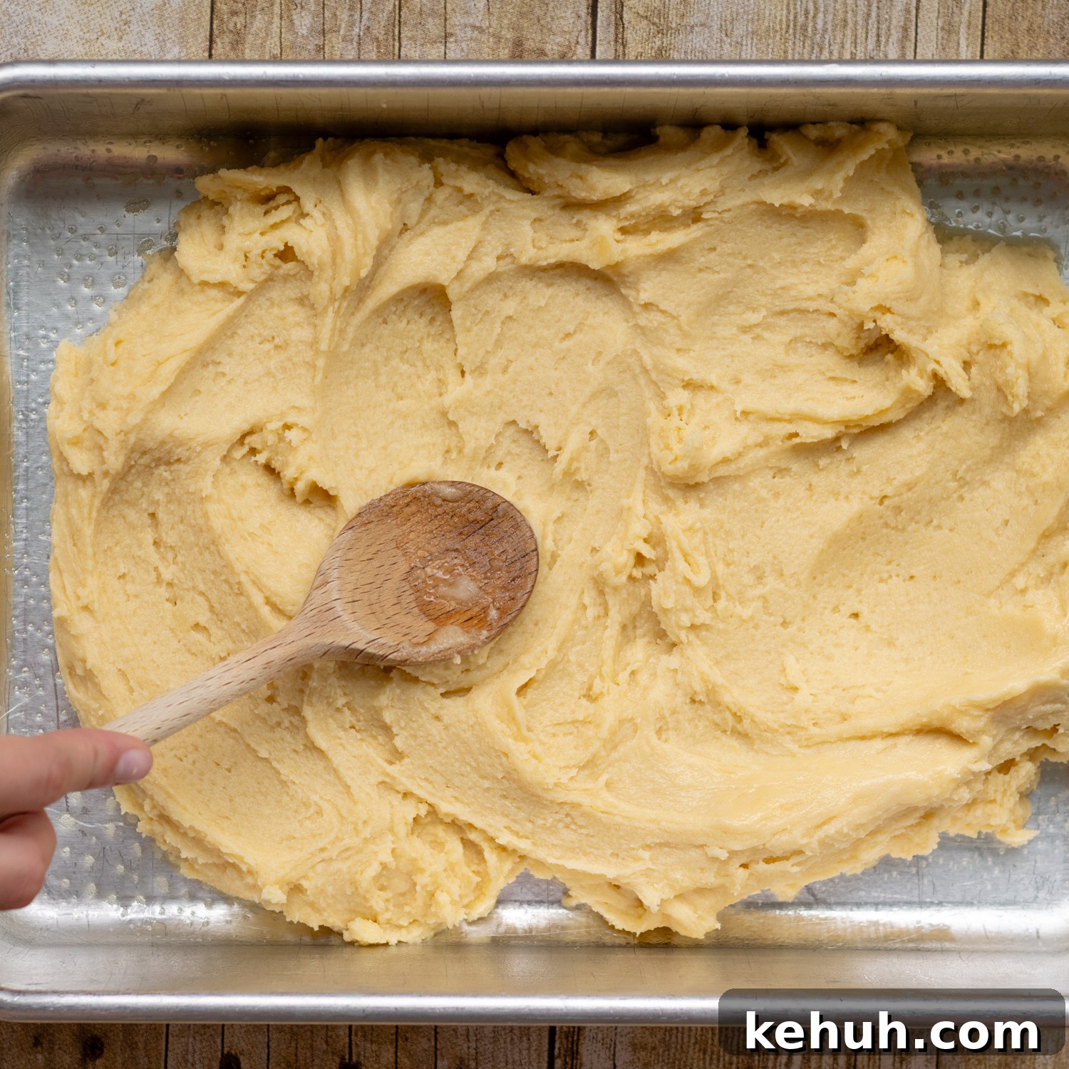 Gooey Snickerdoodle Bars with Cinnamon Frosting Recipe 5 spoon spreading out dough in the pan.