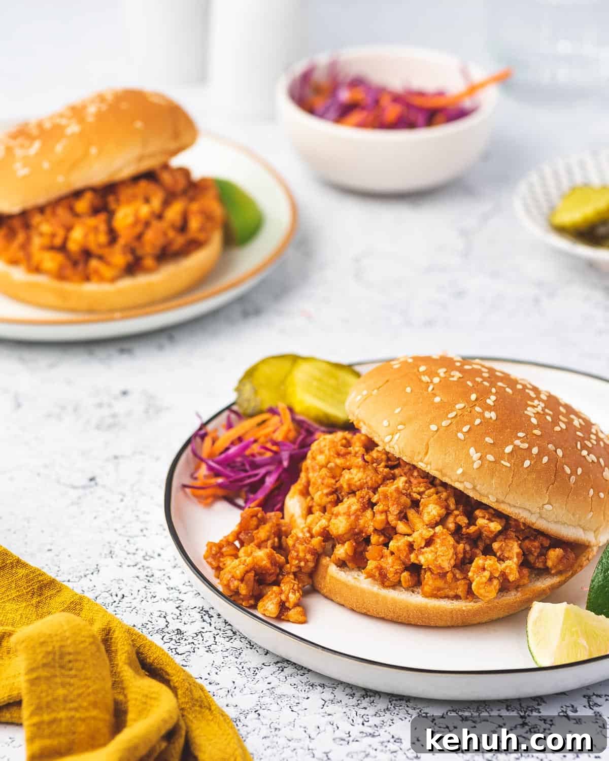 Two plates of chicken sloppy joes in a burger bun.