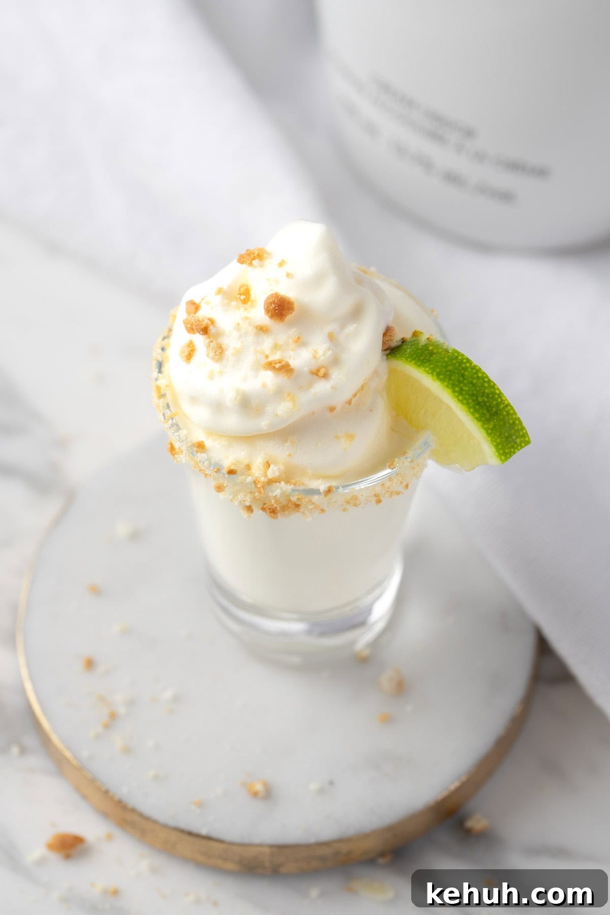 Key Lime Pie Shot Recipe: How to Make the Classic Cocktail Shooter 6 A Key Lime Pie Shot on a white and gold coaster.