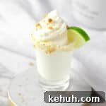 A Key Lime Pie Shot topped with whipped cream, graham cracker sprinkles and a mini slice of lime.