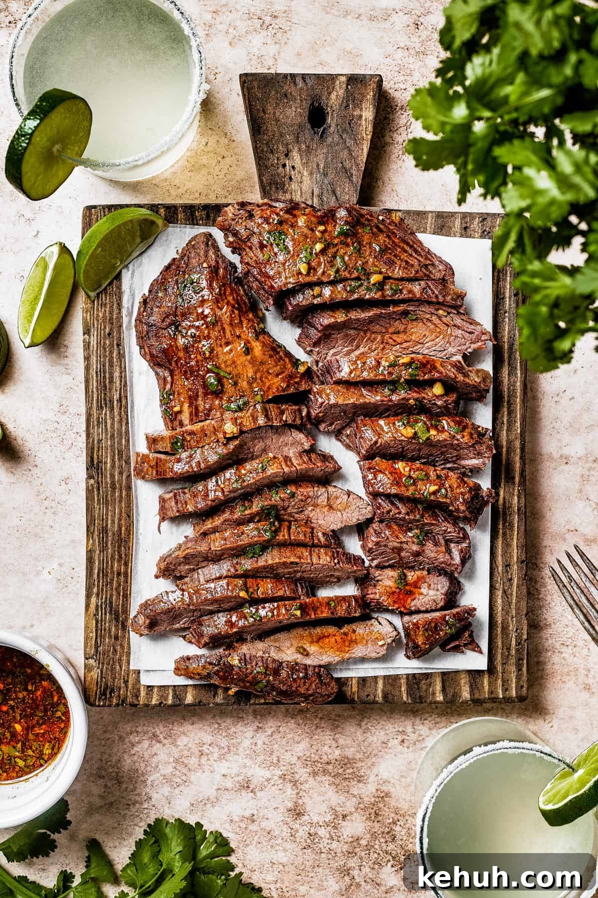 Instant Pot Carne Asada Recipe — Quick Tender Steak Dinner 3 A cutting board with two large pieces of steak, sliced thinly. Limes an cilantro are on the work surface.