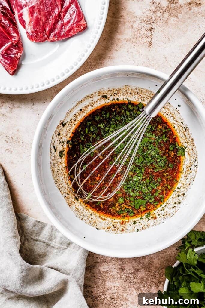 Instant Pot Carne Asada Recipe — Quick Tender Steak Dinner 5 A white mixing bowl with dark-brown marinade and a whisk resting in it.