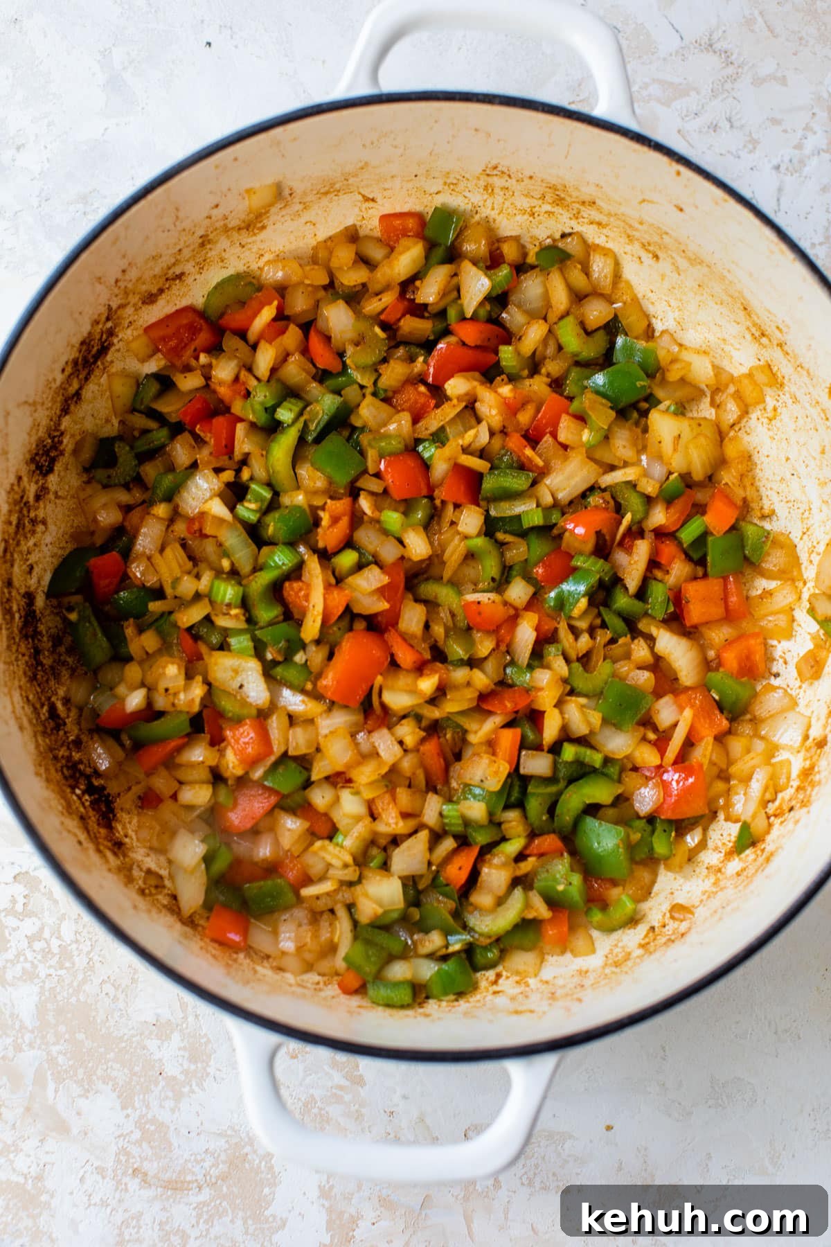 Authentic Chicken and Sausage Jambalaya Recipe for Packed Flavor 4 peppers, onion, and celery cooking in a dutch oven