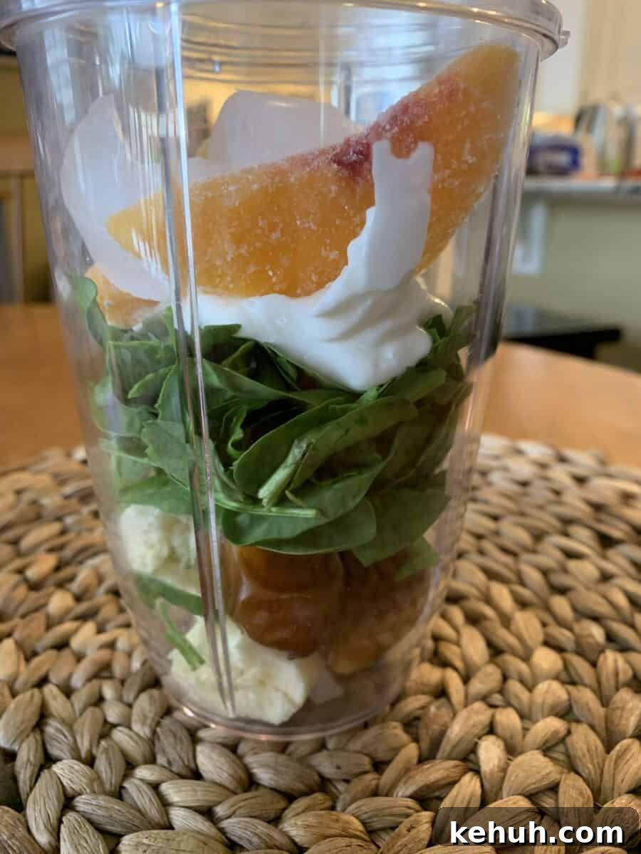 Refreshing Sweet Green Smoothie Recipe for Energy and Glow 8 Peach slices on top of smoothie ingredients in a blender cup