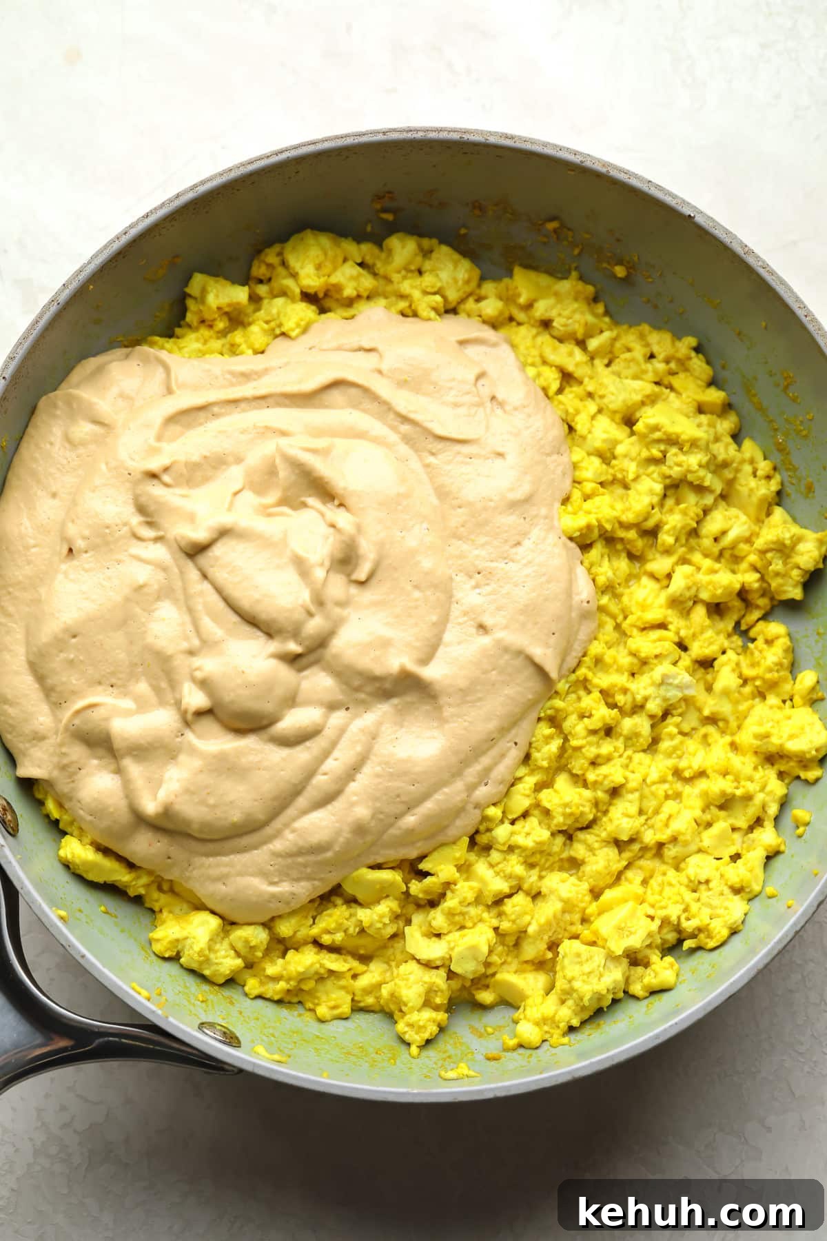 High-Protein Vegan Breakfast Burritos for Busy Mornings 4 tofu scramble yellow with creamy sauce being added to a pan