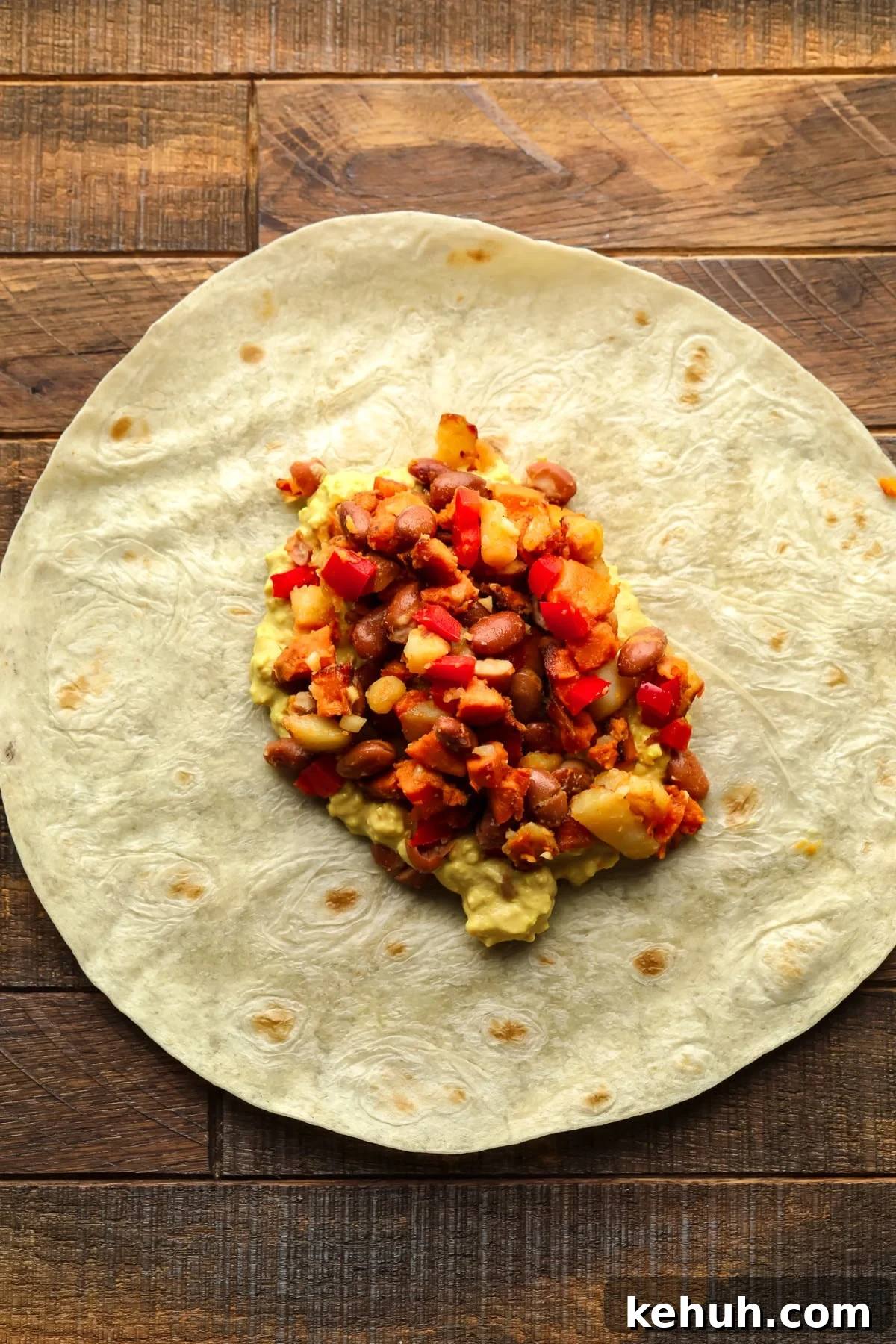High-Protein Vegan Breakfast Burritos for Busy Mornings 6 tortilla on wood board with veggie potato beans and eggy mixture