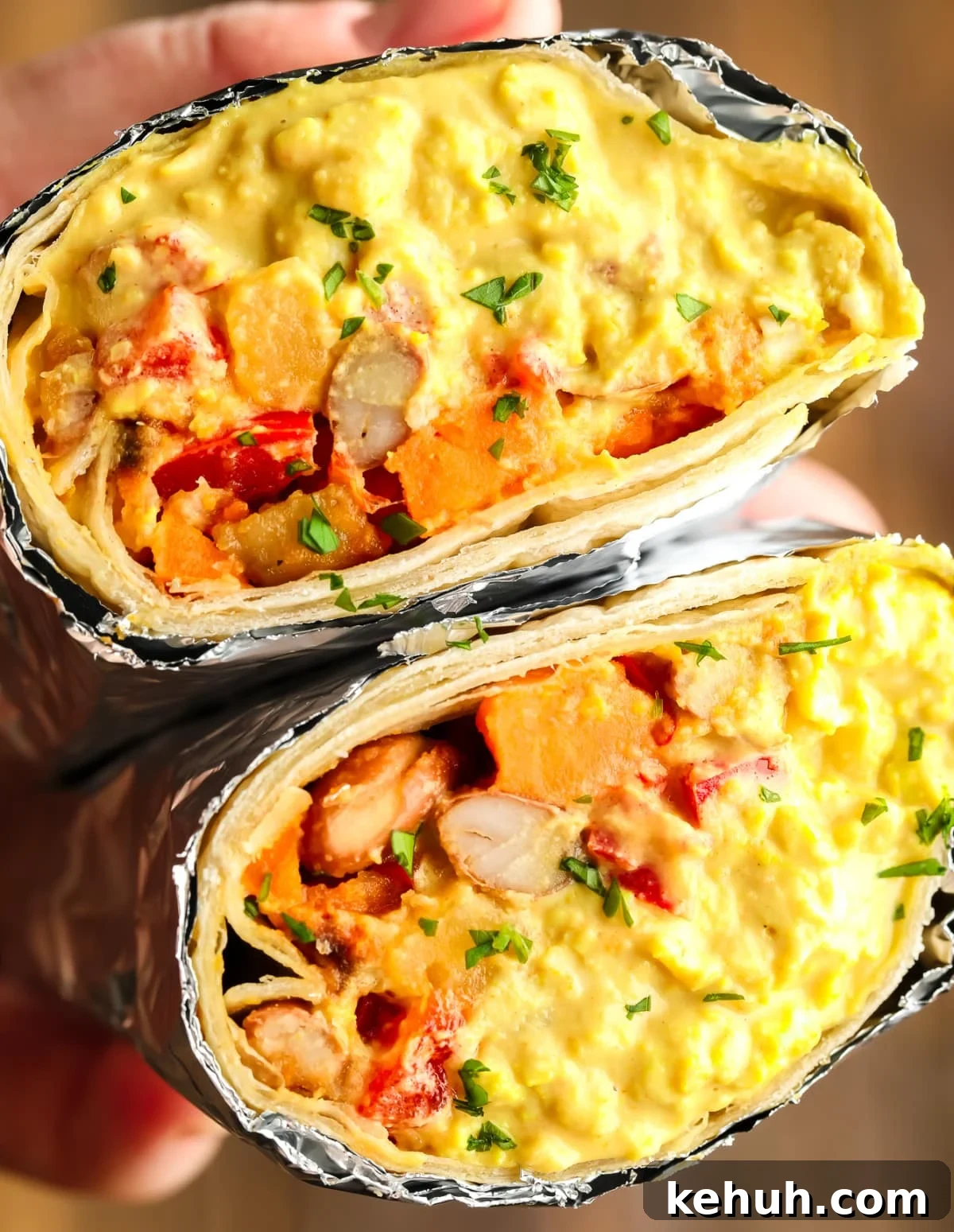 High-Protein Vegan Breakfast Burritos for Busy Mornings 7 yellow eggy looking mixture in vegan breakfast burrito, a hand holding a cut in half burrito