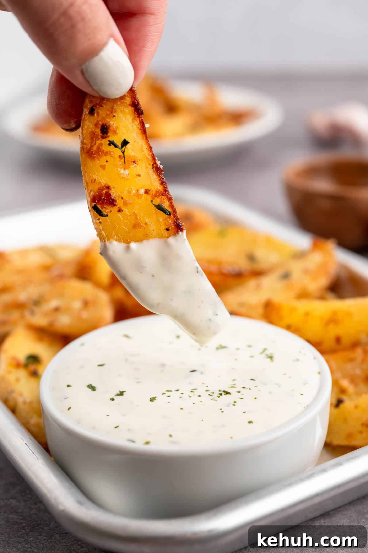 Crispy Parmesan and Thyme Roasted Potatoes Recipe 8 A hand dipping parmesan thyme roasted potato into ranch dip.