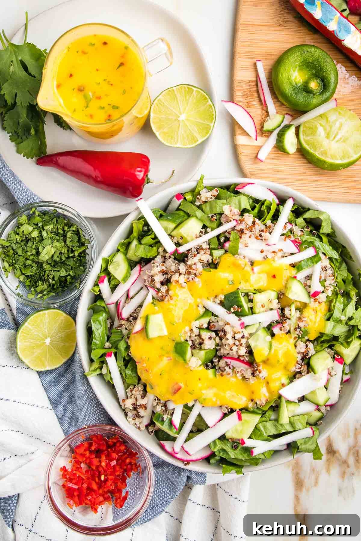 Vibrant Vegan Mango Salad Dressing Recipe for Fresh Salads 2 Bright yellow mango salad dressing in a glass pitcher, a bowl of simple salad with same yellow dressing, lots of colorful chopped veggies strewn about.