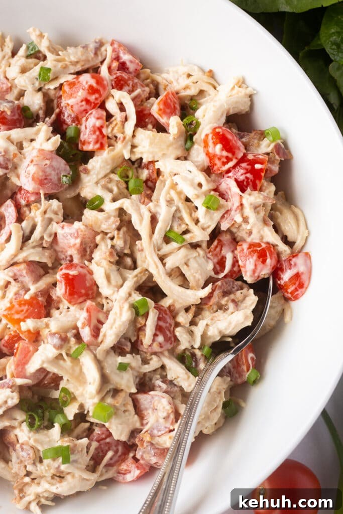 5-Ingredient BLT Chicken Salad Recipe for Quick Lunch 2 Close up of some BLT chicken salad in a large white bowl with a spoon sticking in it.
