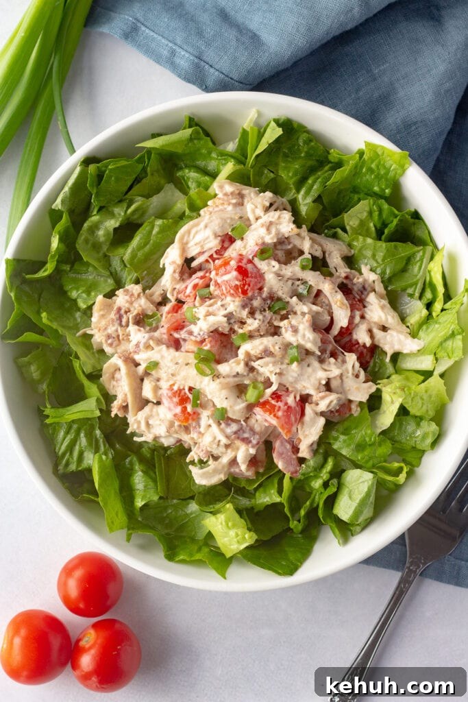 5-Ingredient BLT Chicken Salad Recipe for Quick Lunch 13 Top down shot of BLT chicken salad on top of a bed of greens in a white low bowl.