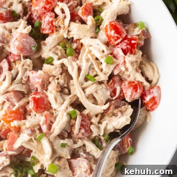 5-Ingredient BLT Chicken Salad Recipe for Quick Lunch 15 Close up of some BLT chicken salad in a large white bowl with a spoon sticking in it.