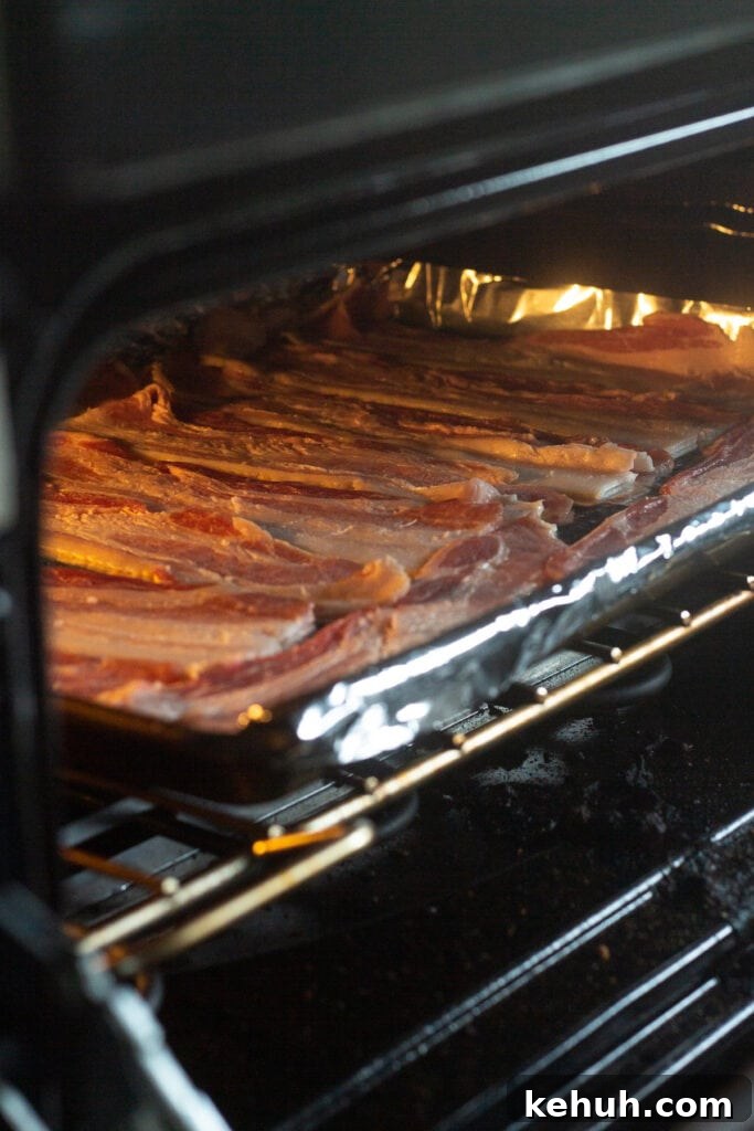 5-Ingredient BLT Chicken Salad Recipe for Quick Lunch 5 Raw bacon on a foil-lined baking sheet going into a cold oven.