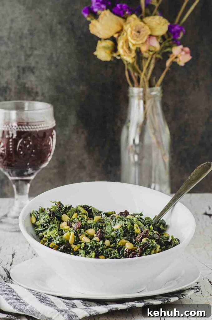 Side view of a white bowl filled  with Catalan spinach ( spinach with pine nuts and raisins)