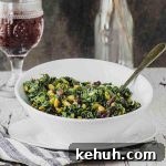 Side view of a white bowl filled with spinach with pine nuts and a raisins with a glass of red wine in the background.