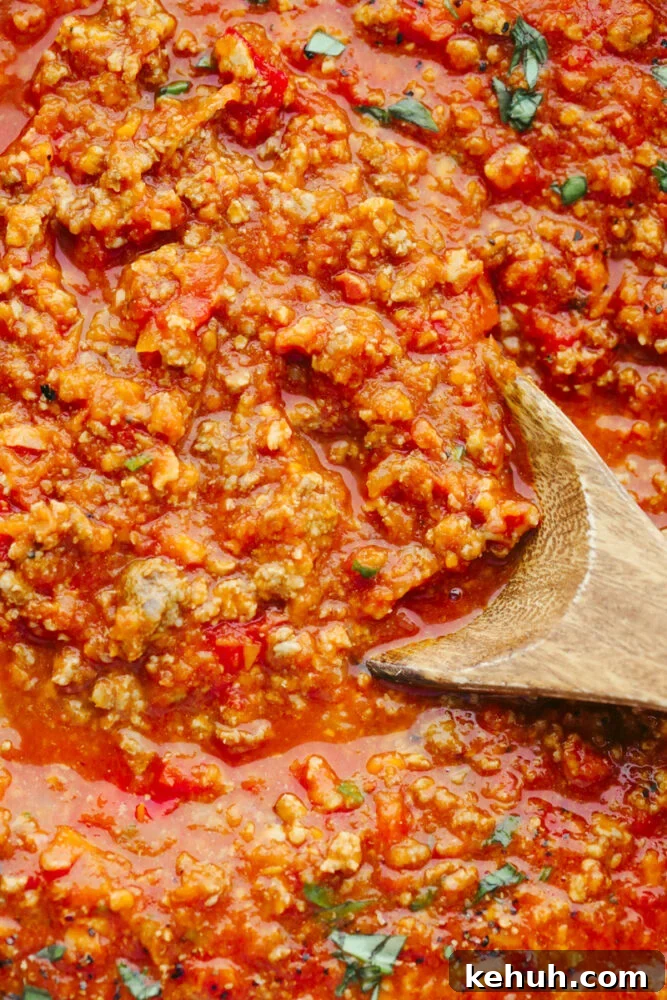 Zoomed in picture of the sauce with a wooden spoon in it. 