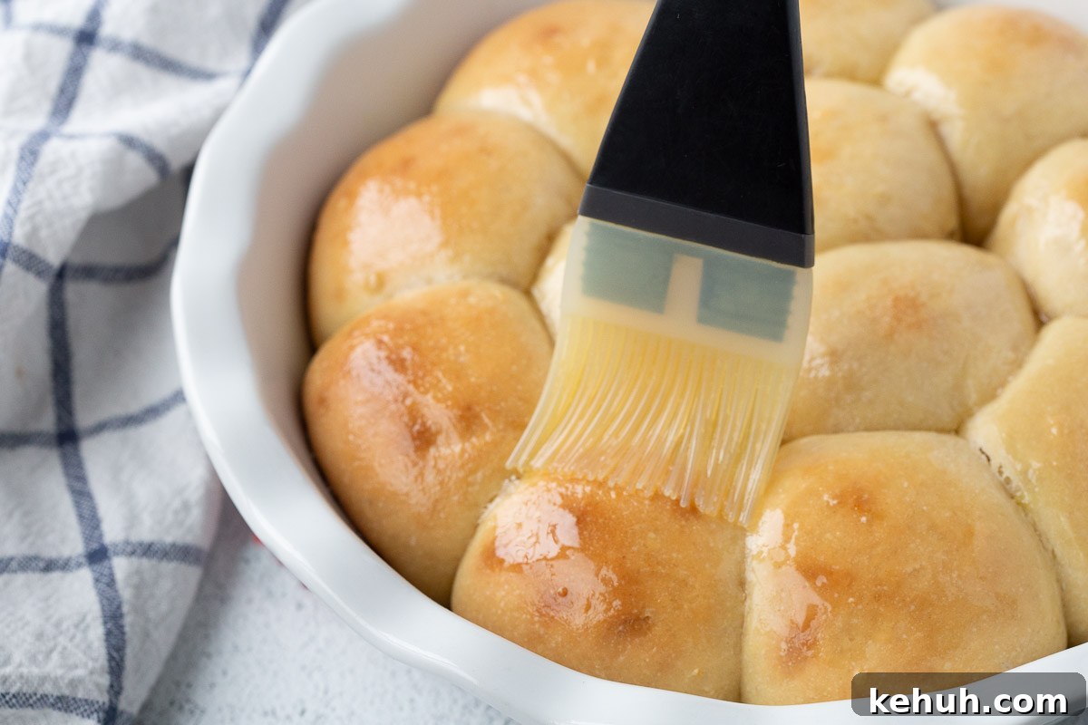 Fluffy Mashed Potato Dinner Rolls: Soft, Buttery Recipe 11 pastry brush brushing potato rolls with butter.