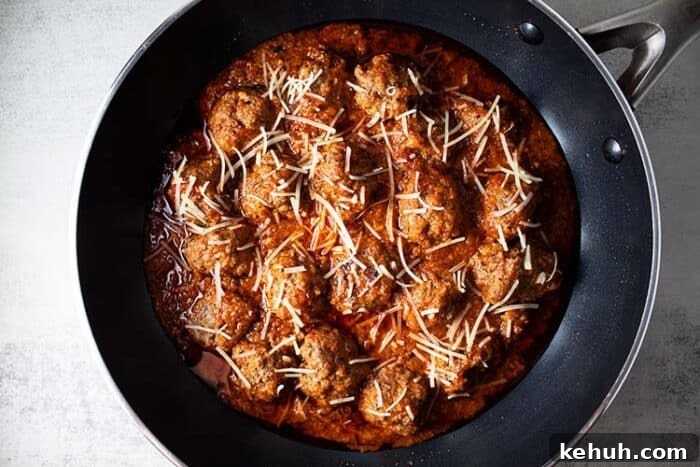 Keto 4th of July Recipes for Your Patriotic Cookout 17 overhead view of keto meatlballs in marinara sauce topped with shredded parmesan cheese in a black skillet