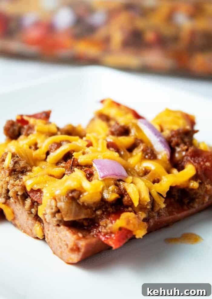 Keto 4th of July Recipes for Your Patriotic Cookout 33 piece of keto chili dog casserole on a white plate with casserole dish in background