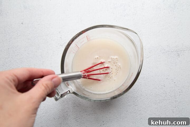 Fluffy Mashed Potato Dinner Rolls: Soft, Buttery Recipe 5 hand whisking yeast into a glass measuring cup of water.