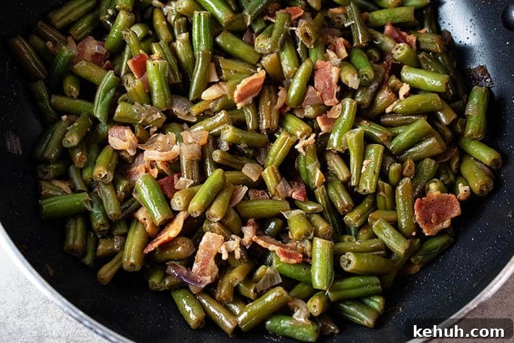 Keto 4th of July Recipes for Your Patriotic Cookout 61 overhead view of skillet on stovetop with cooked bacon green beans after combining and cooking