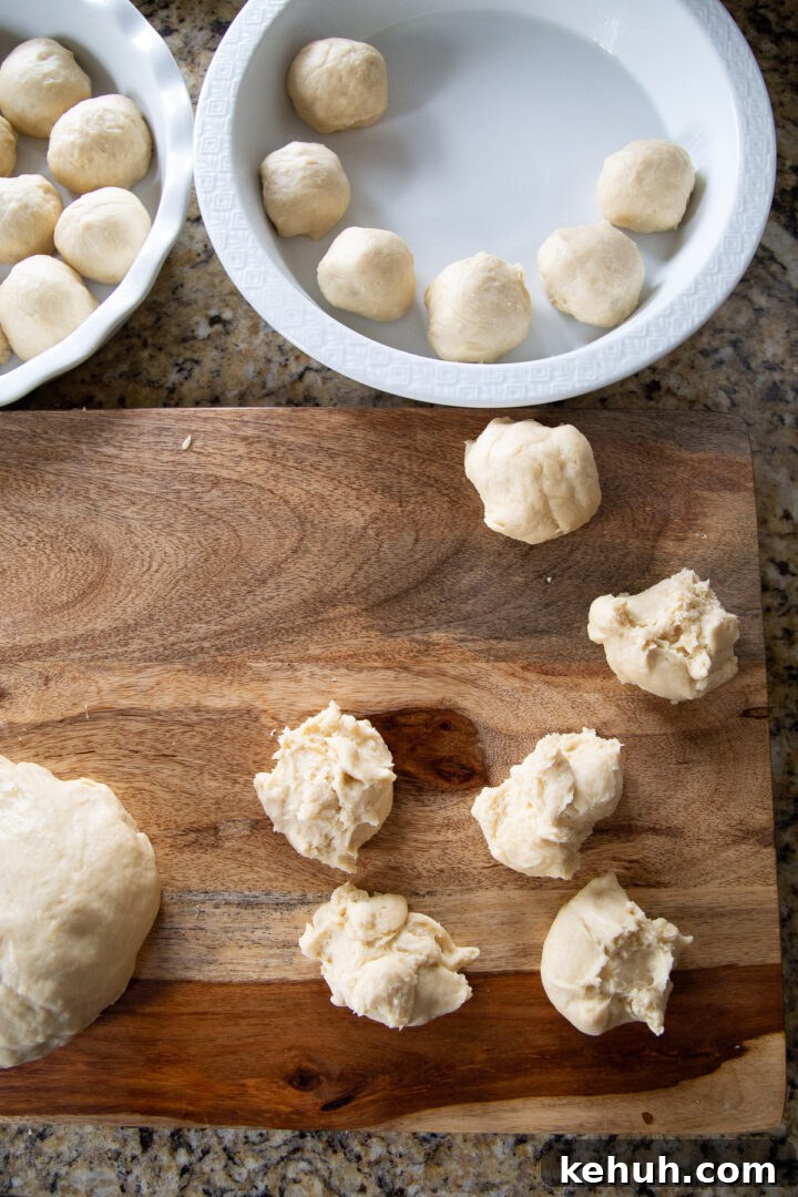 Fluffy Mashed Potato Dinner Rolls: Soft, Buttery Recipe 9 balls of bread dough on a cutting board and in cake pans.