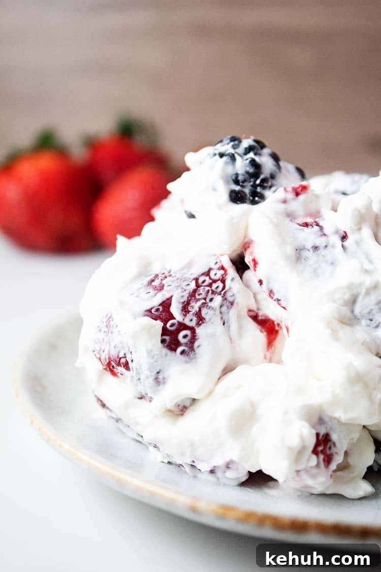 Keto 4th of July Recipes for Your Patriotic Cookout 73 sideview of healthy keto cheesecake fluff on a white serving dish with strawberries in the background