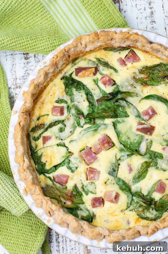 Spinach, Ham & Cheese Quiche Recipe for Brunch and Weeknights 6 A baked ham and cheese quiche with a green napkin next to it.
