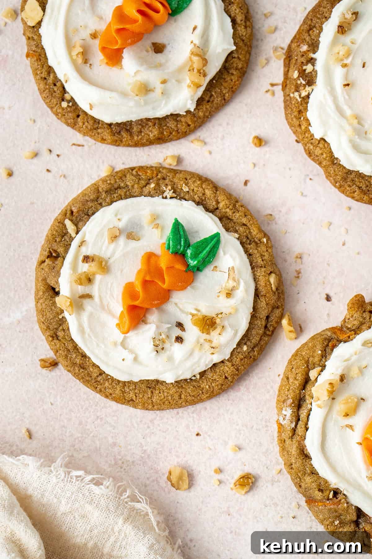 Frosted vegan carrot cake cookies decorated with piped carrots and chopped walnuts.