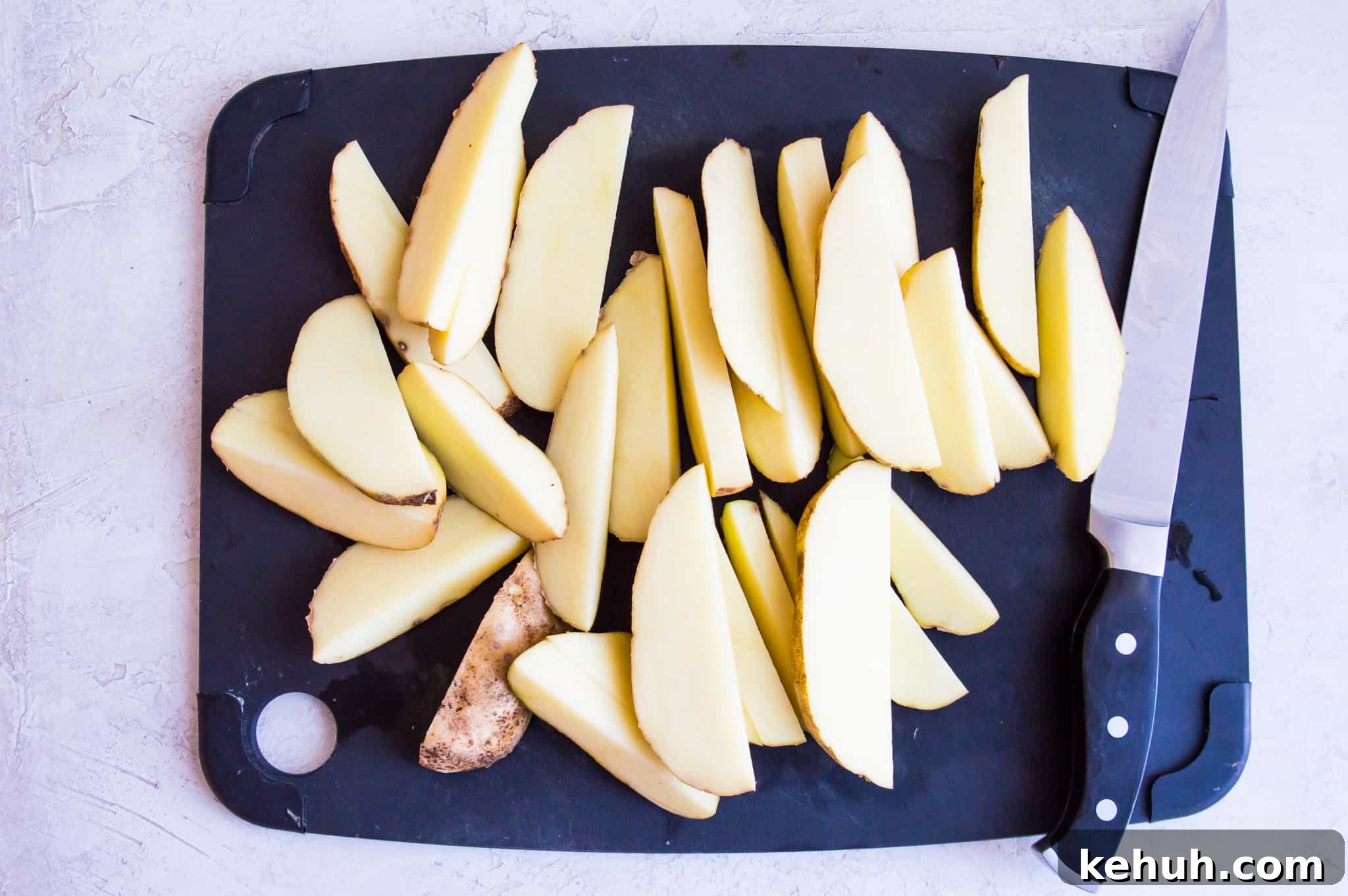 Chopped potatoes on a cutting board with a knife beside them.