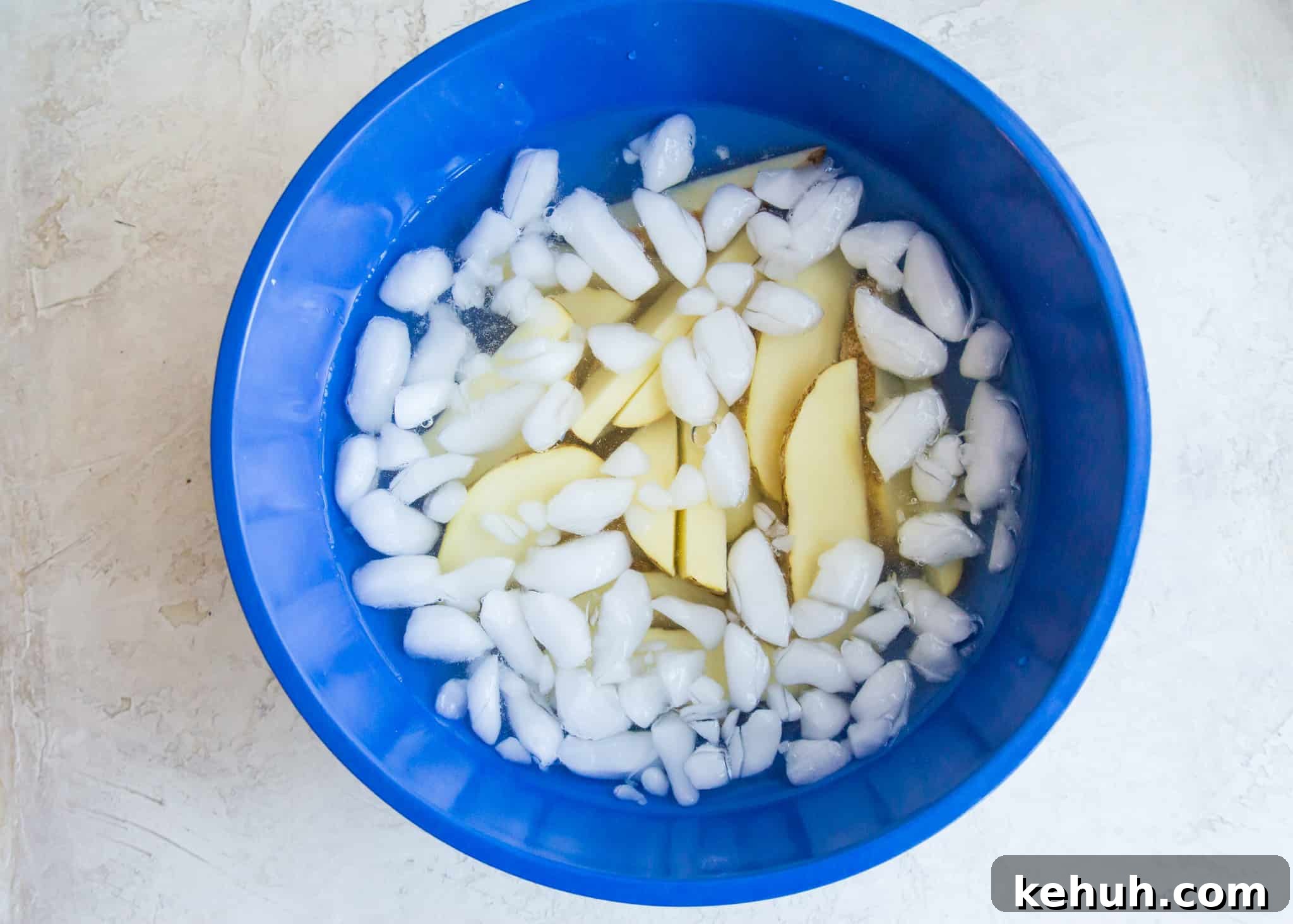 Potato wedges soaking in a bowl of ice water.
