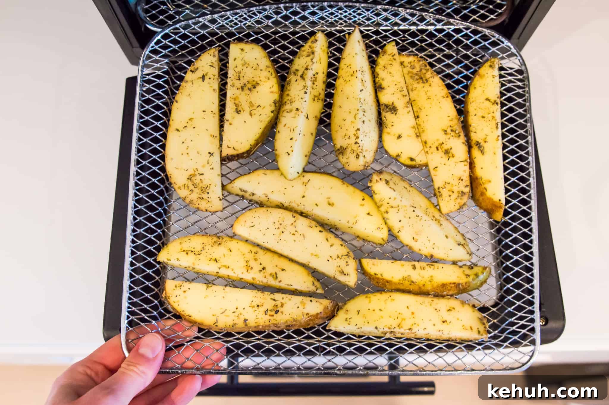 Sliced potatoes on an air fryer tray.