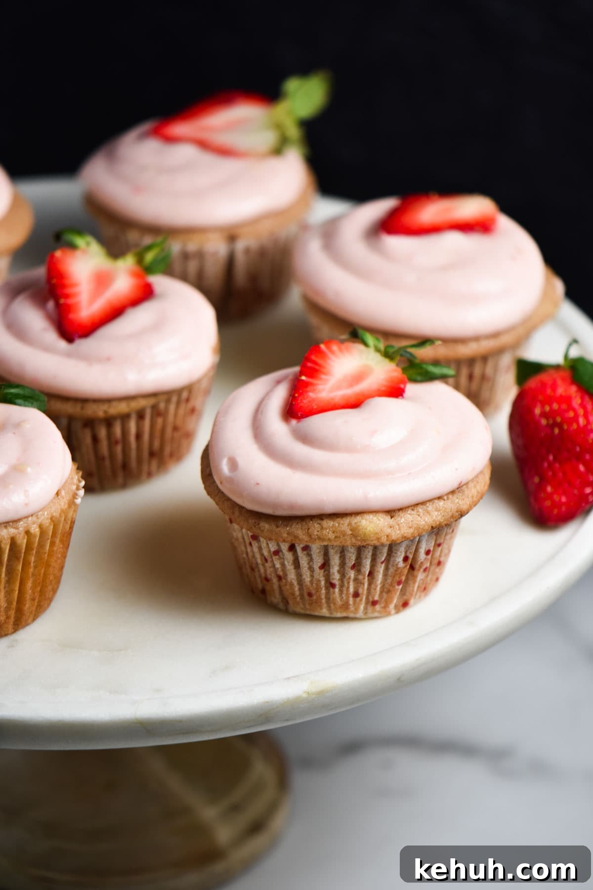 Gluten-Free Strawberry Cupcakes with Cream Cheese Frosting 2 Pink gluten free strawberry cupcakes on a marble table.