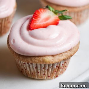 Gluten-Free Strawberry Cupcakes with Cream Cheese Frosting 12 A pink strawberry cupcake with cream cheese frosting and a fresh strawberry on top.