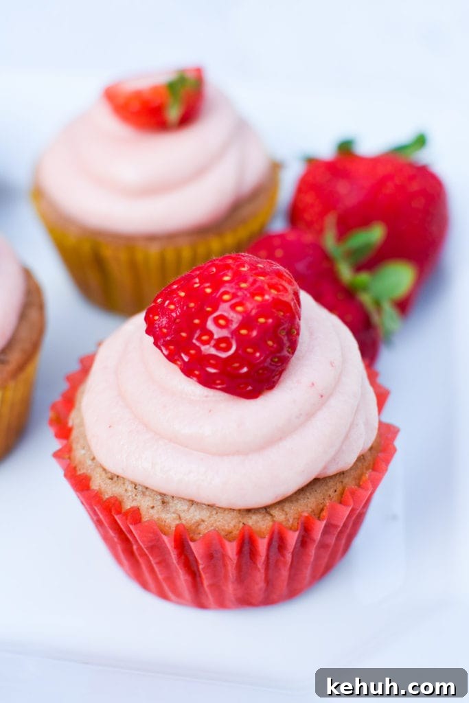 Gluten-Free Strawberry Cupcakes with Cream Cheese Frosting 13 Gluten free strawberry cupcake with pink frosting in a red cupcake holder on a white plate.