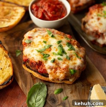 Crispy Chicken Parmesan Sandwich Recipe with Melty Mozzarella 2 parmesan chicken sandwich on chopping board surrounded by basil, parmesan and ciabatta