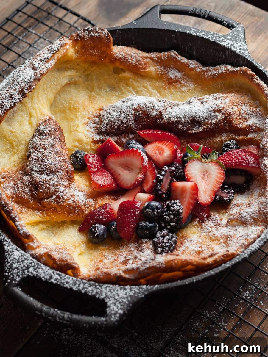 Gluten-Free Dutch Baby Pancake Recipe for Fluffy Oven Pancakes 7 a gluten free dutch baby in a cast iron pan. dusted with powdered sugar and topped with fresh fruit