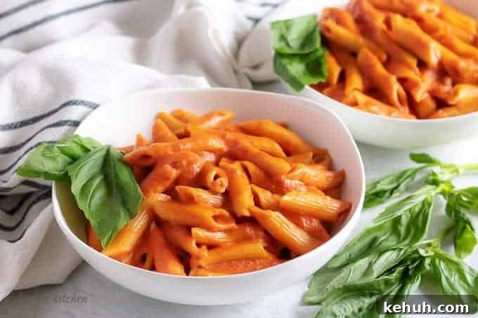 Two bowls of penne with vodka sauce and basil.