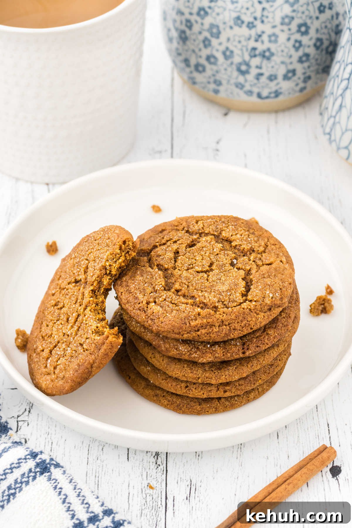 Chewy Molasses Crinkle Cookies Recipe 7 A cookie with a bite taken out of it on a white plate.