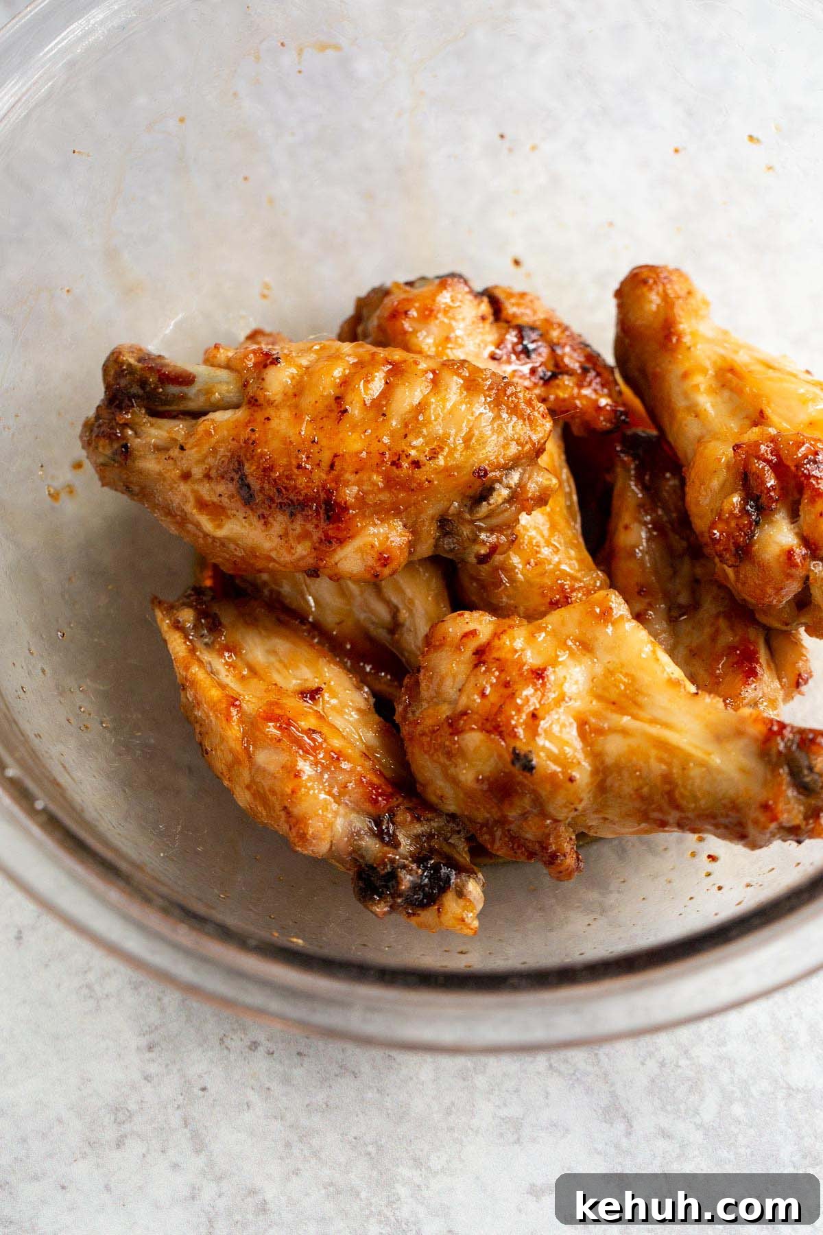 Chicken wings in a bowl tossed with honey garlic sauce.