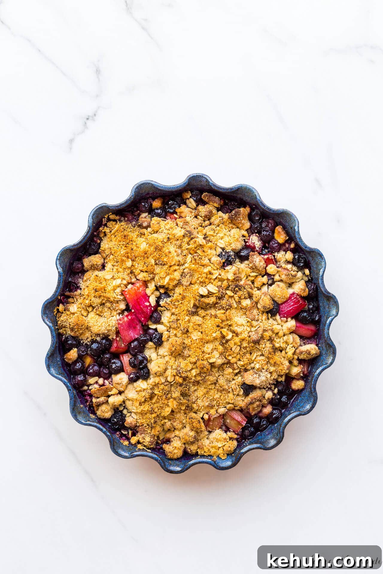 Complete Guide to Baking Pans and Bakeware Types 12 Blueberry rhubarb crumble with a marzipan oat crumble topping served in a round ceramic blue baking dish with a fluted edge