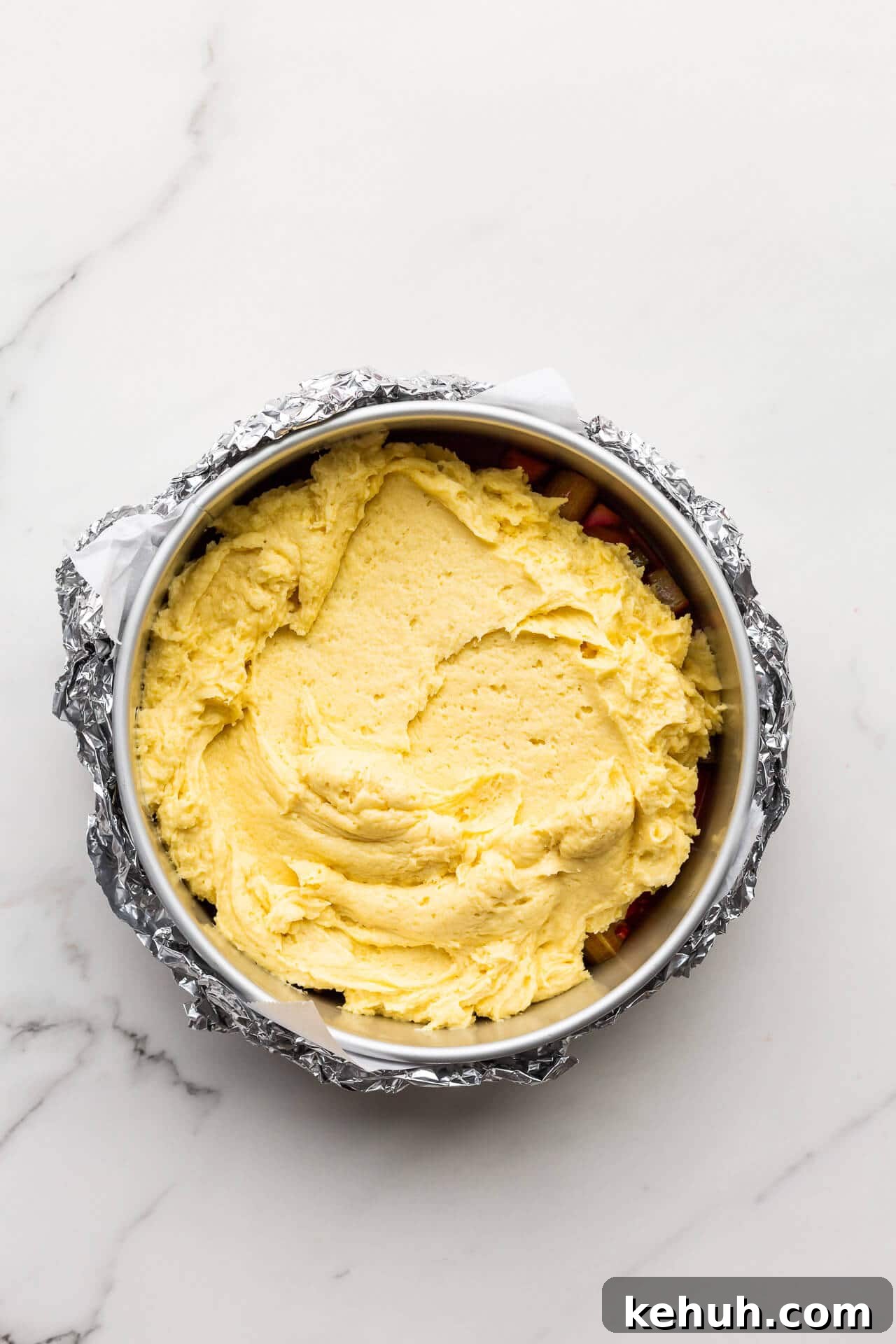 Complete Guide to Baking Pans and Bakeware Types 3 Spreading cake batter over a fruit and caramel layer to make an upside down cake in a springform pan wrapped in foil to stop the juices from leaking out