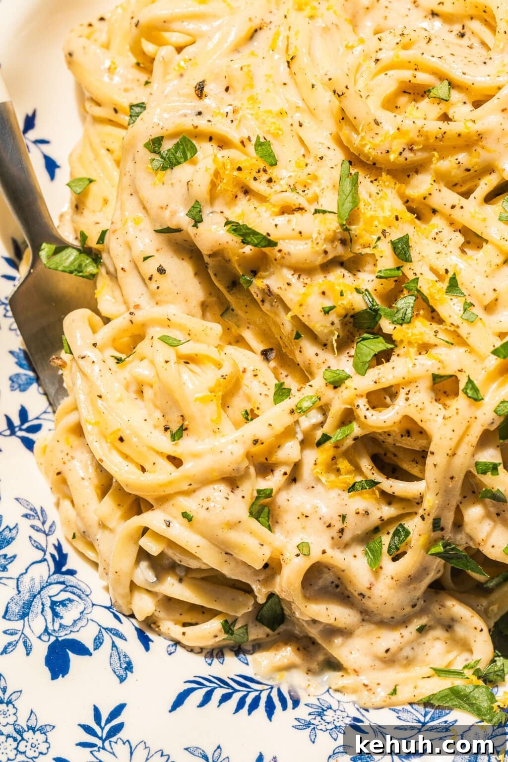 close up photo of lemon pasta with a creamy sauce and green garnish